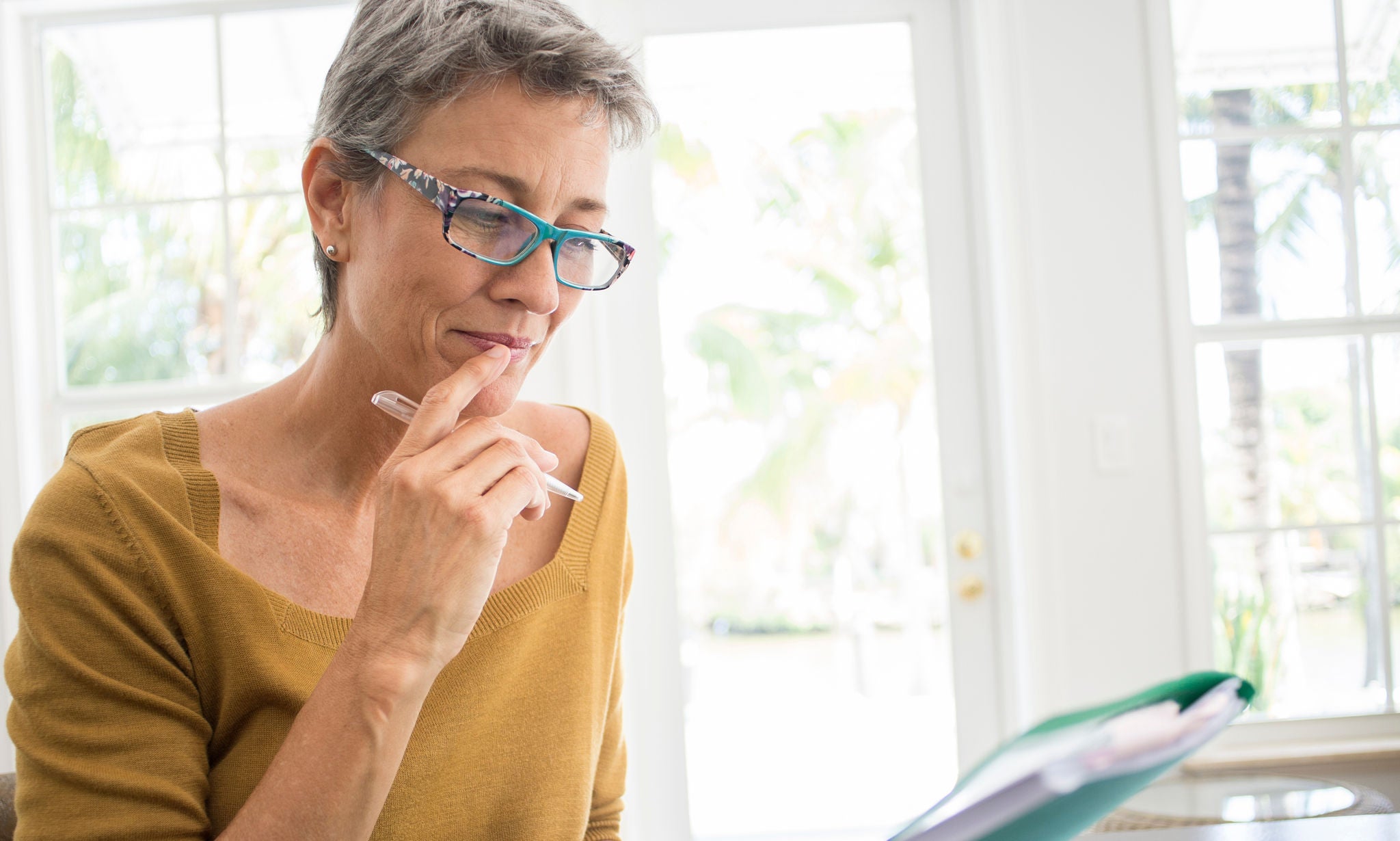 Woman reading folder at desk in living room